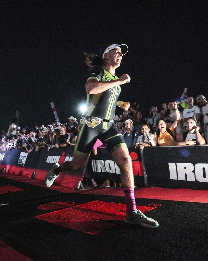 Anxo cruzando la línea de meta de un IRONMAN de noche