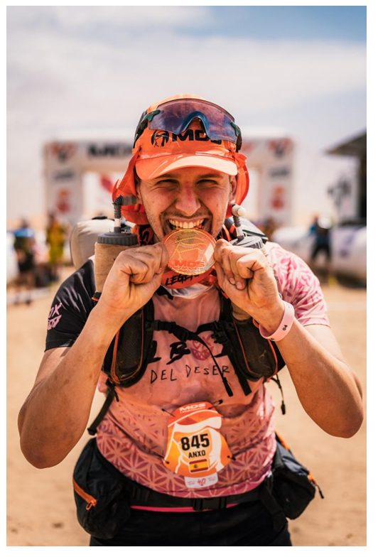 Anxo mordiendo la medalla de finisher del Marathon des Sables